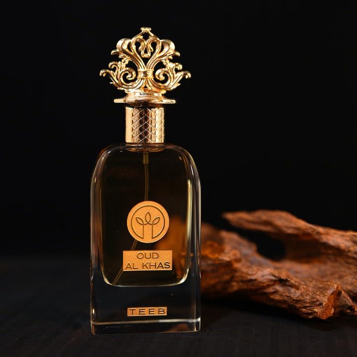 Oud Al Khas bottle with amber liquid and ornate gold cap on a dark background beside a piece of dark wood