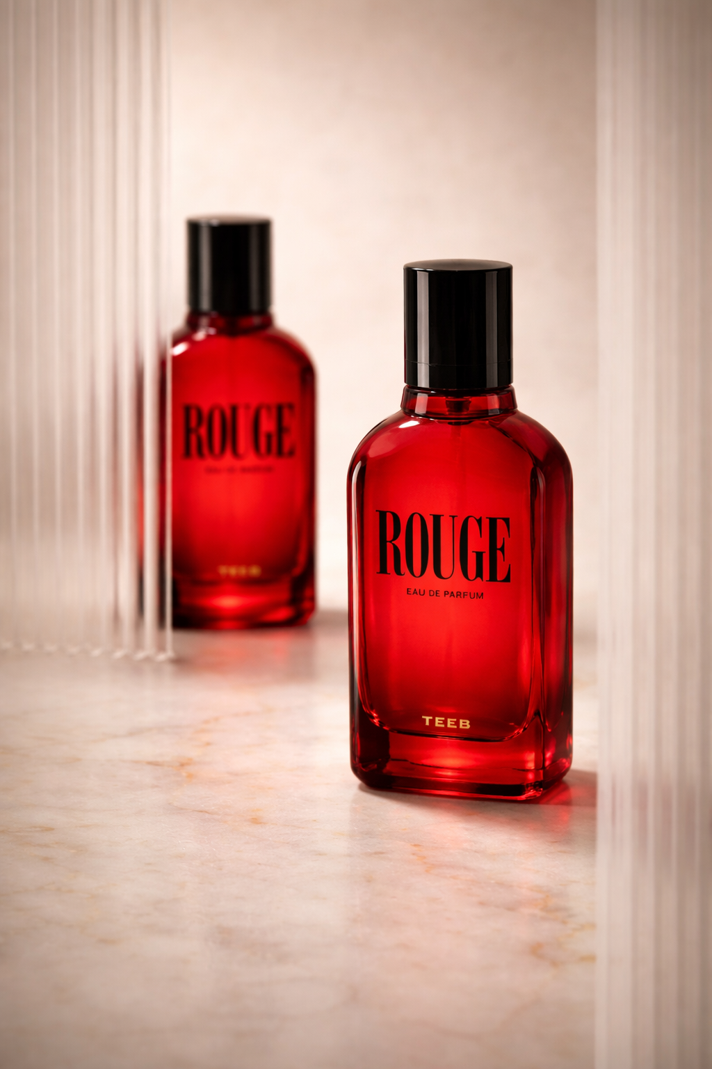 Two red Rouge Eau de Parfum bottles with black caps on a marble surface beside ribbed glass panels