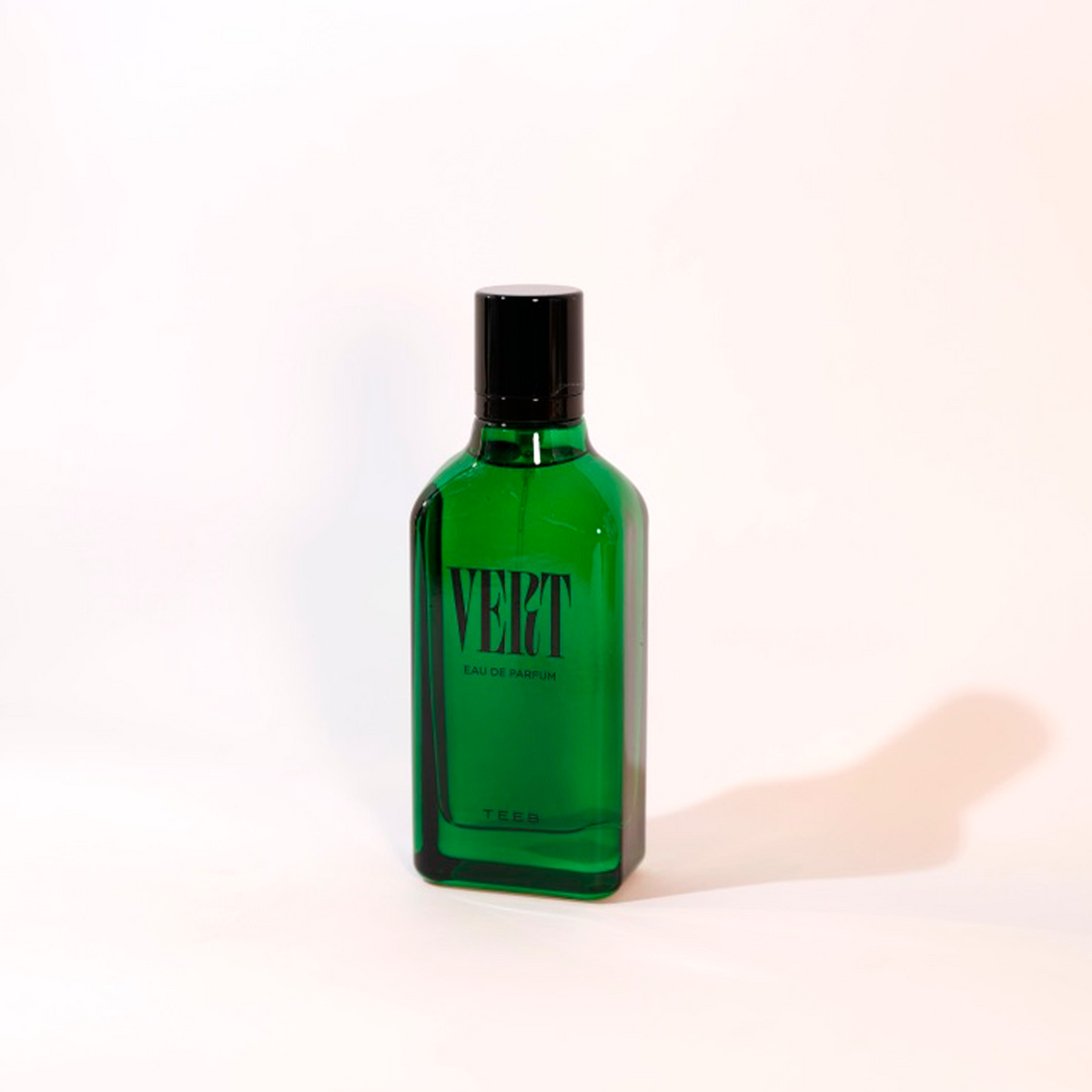 Vert Eau de Parfum green glass bottle with black cap on a soft ivory background
